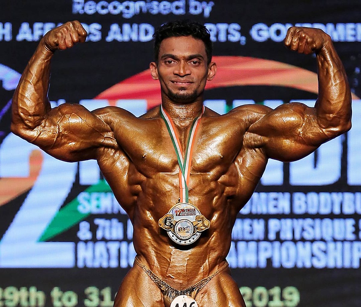 Sunit Jadhav hitting a front double biceps on stage